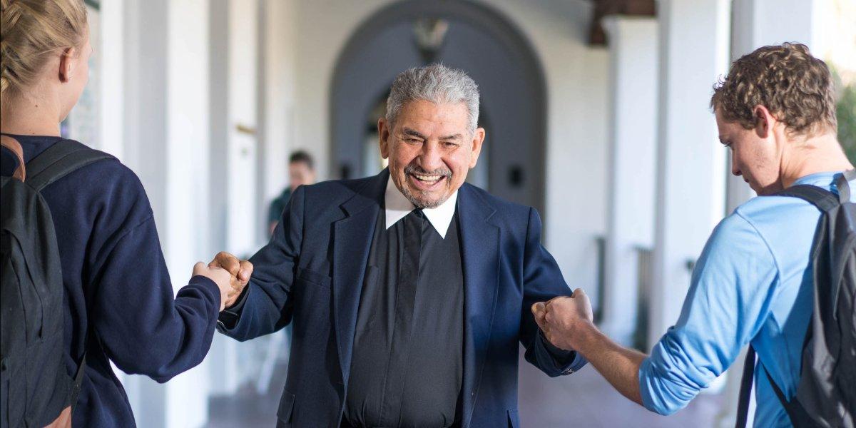 Brother Camillus Chavez fistbumping two students