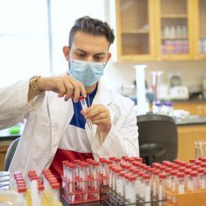 1 male lab student working with samples in vials in a lab