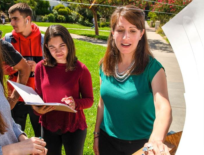 student and teacher examine object during outdoor class